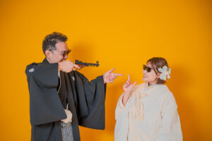 和装を着た男性が女性に向かって指を指し、女性はサングラスをかけている。