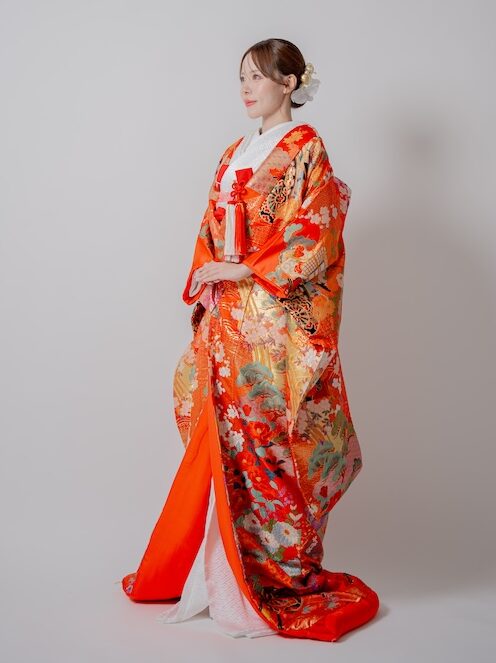 御所車が背中に大きく描かれた赤の色打掛 横を向いて手を合わせている花嫁様 大阪和装ウェディングフォトスタジオでの撮影
