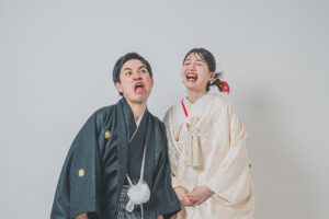 和装を着た男女が笑顔でポーズをとっている。男性は黒い着物、女性は白い着物を着用している。