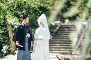 和装を着た男女が静かな場所で向かい合っている。男性は黒い羽織を着ており、女性は白い打掛を着用している。