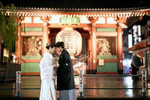 和装を着たカップルが夜の浅草寺の前で向き合っているシーン。背景には大きな提灯が見える。