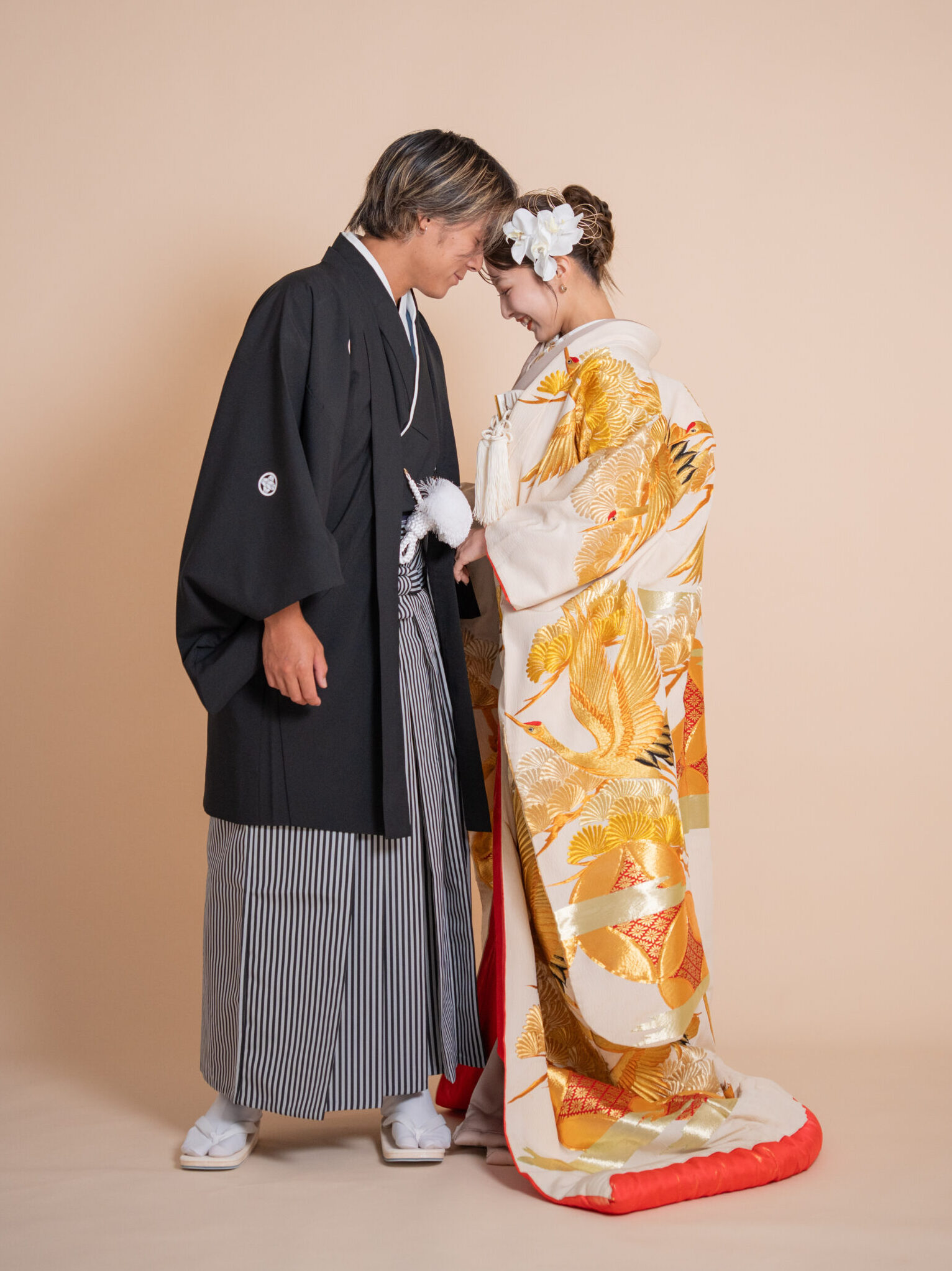 ゴールドの色打掛と黒紋付羽織袴が華やかに調和する和装カップルショット