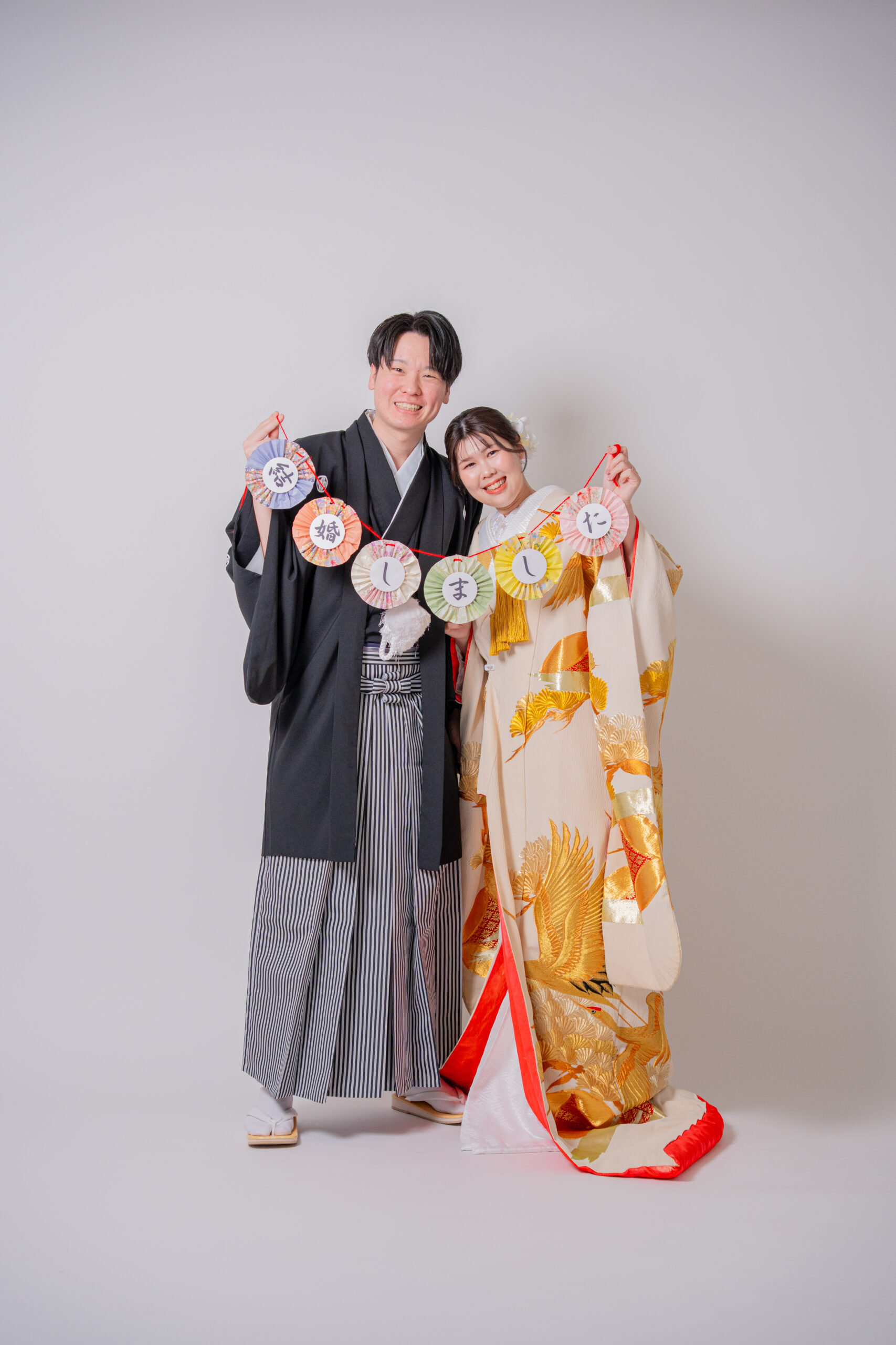 結婚しましたと書かれたガーランドを手に持って撮影する和装カップル 大阪