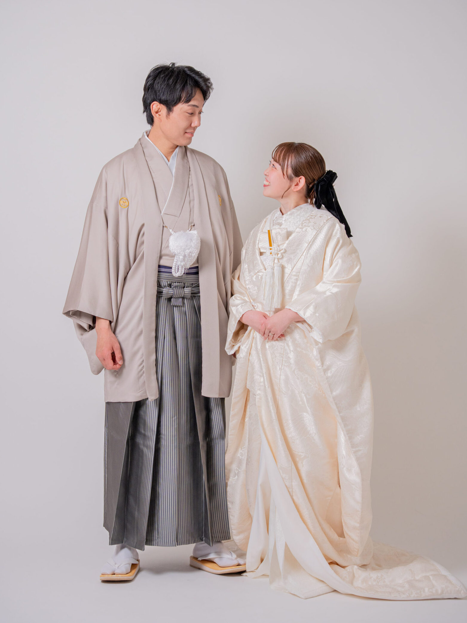 グレージュの紋付姿の新郎と白無垢姿の花嫁が優しく見つめ合う美しいカップルショット