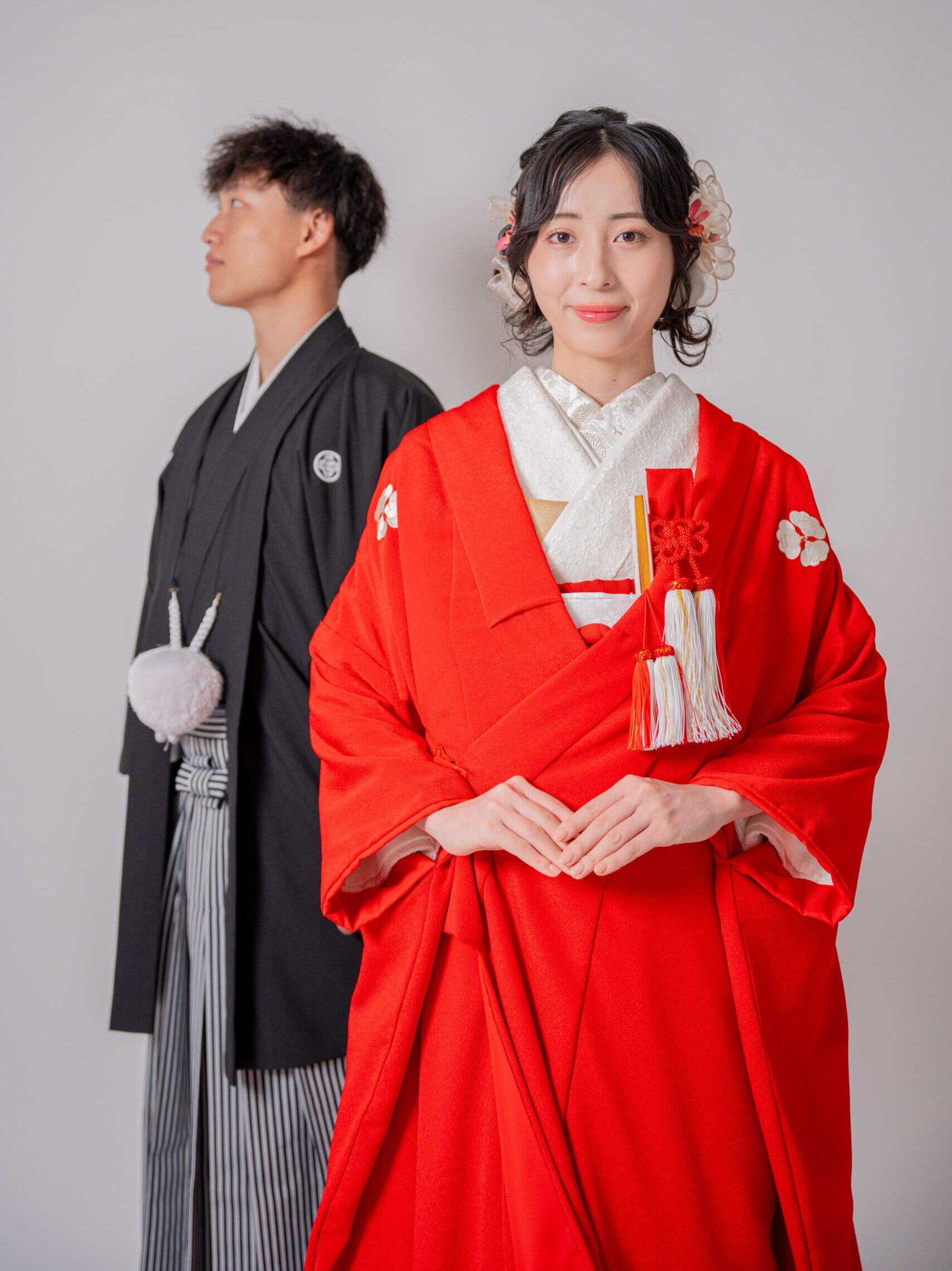 赤一色に染められた赤無垢 洗練された美しい花嫁様の後ろから黒紋付の新郎が優しい眼差しで横を向いている 和装前撮りポーズ