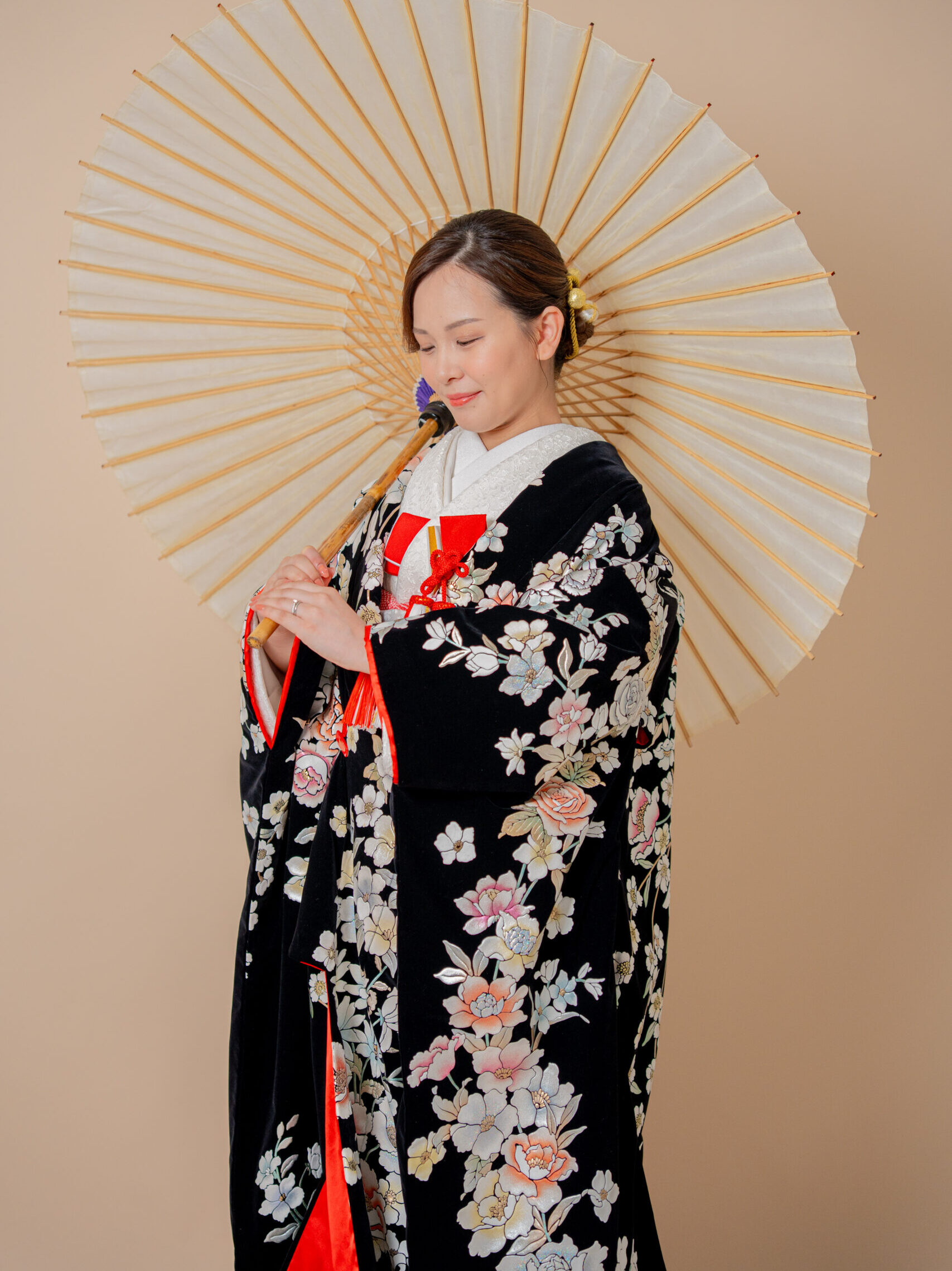 ベルベット生地黒打掛をまとい後ろ向き白い番傘に手を添える和装花嫁 和装前撮りスタジオ大阪