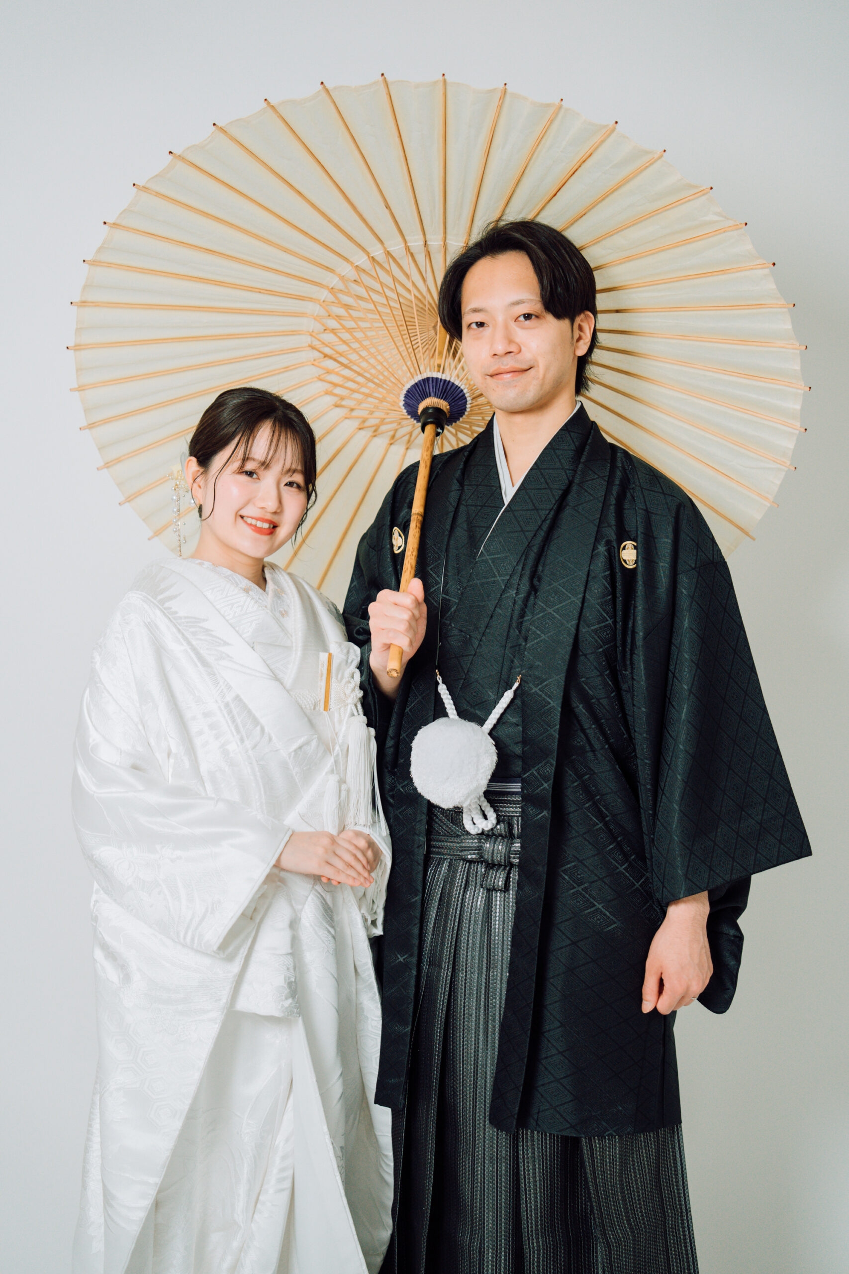 白い番傘を手に正面を向く新郎新婦 和装前撮り