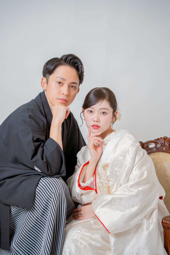 白無垢姿の花嫁と黒紋付き新郎の顔に手を当ててカメラ目線のおしゃれなショット