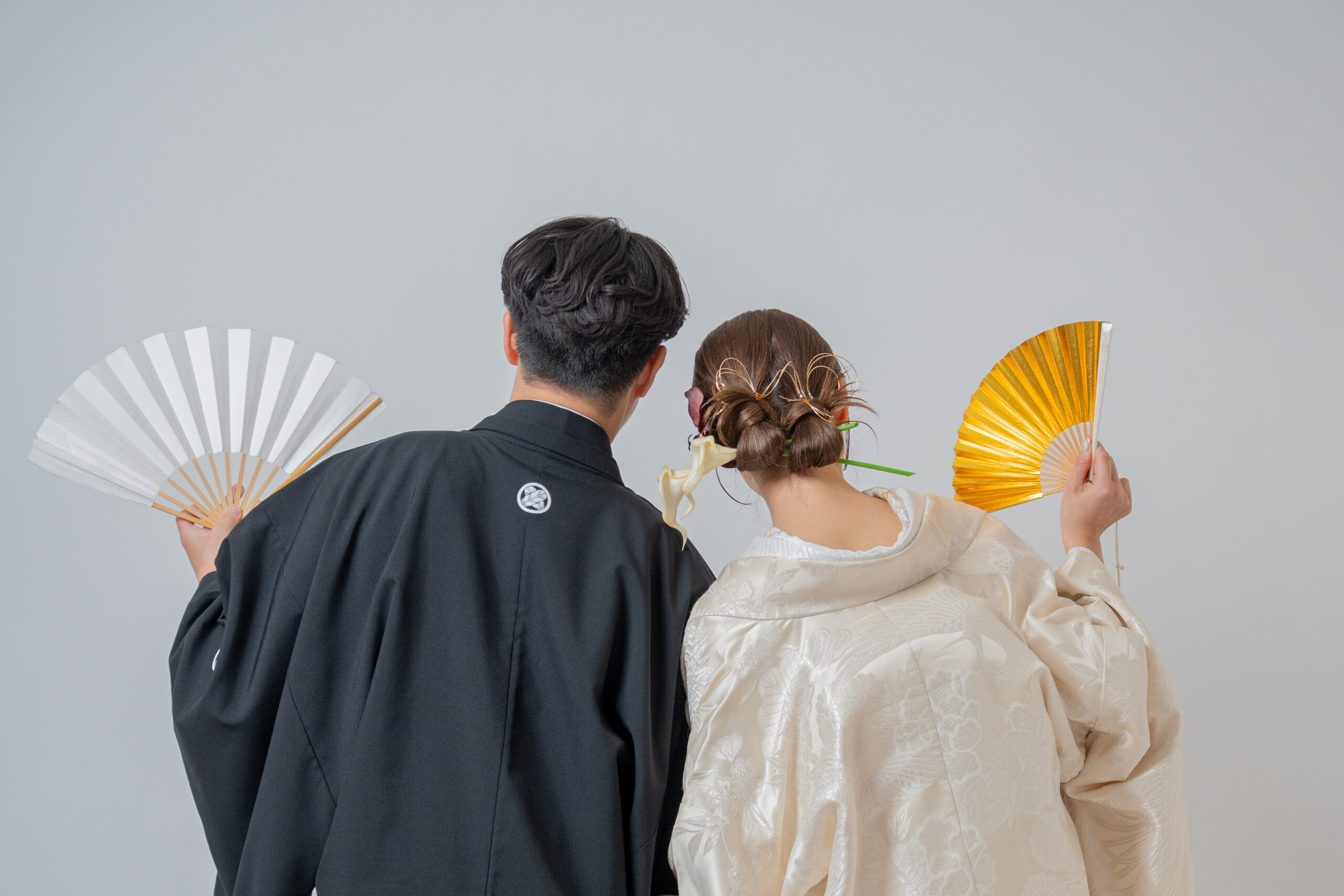 白無垢と黒紋付で末広を持って後ろ姿を撮影するウェディングフォト