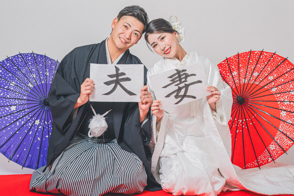 習字で妻夫と書かれたアイテムを手に持って正座で撮影する和装ポーズ