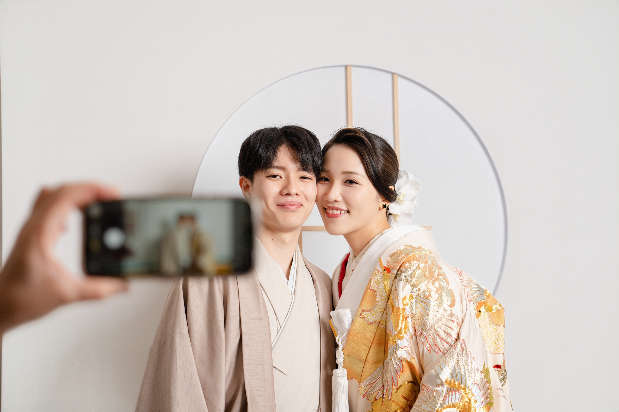 ゴールドの色打掛とカフェラテの色紋付の新郎新婦 障子窓の前でオフショット撮影の様子