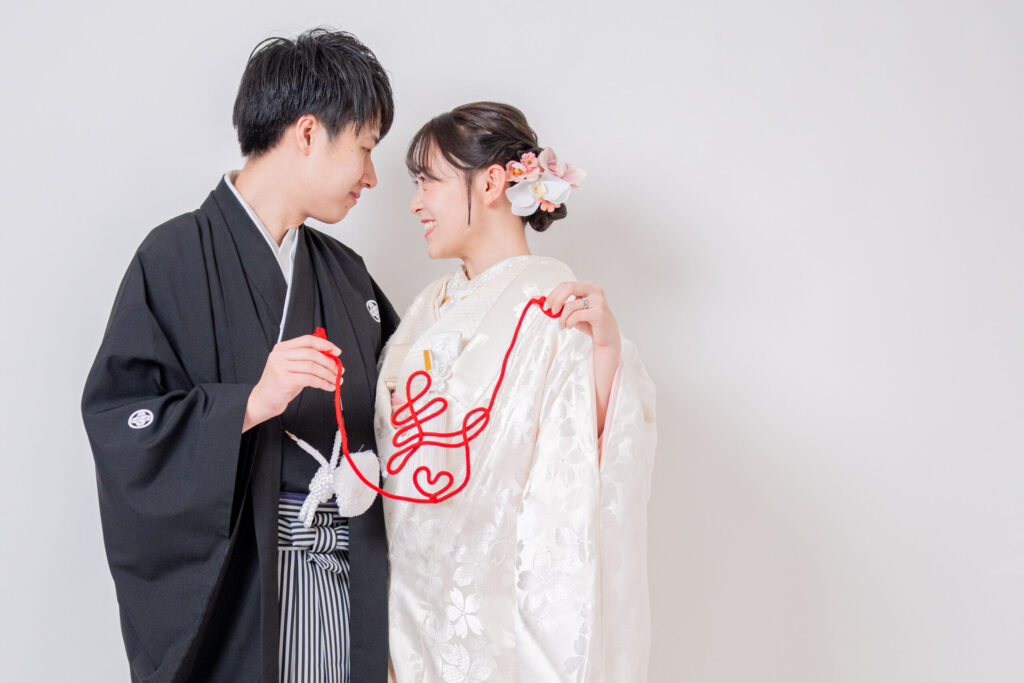 ピンクの桜模様の白無垢 寿の赤い糸を持って向き合うポーズ 和装前撮りを楽しむカップル様