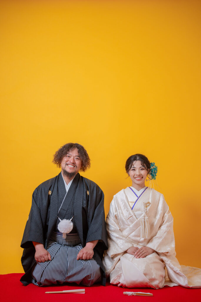 INAI WEDDING WASOUの和装前撮り・後撮り｜スタジオで正座して微笑む白無垢の新婦と紋付袴の新郎