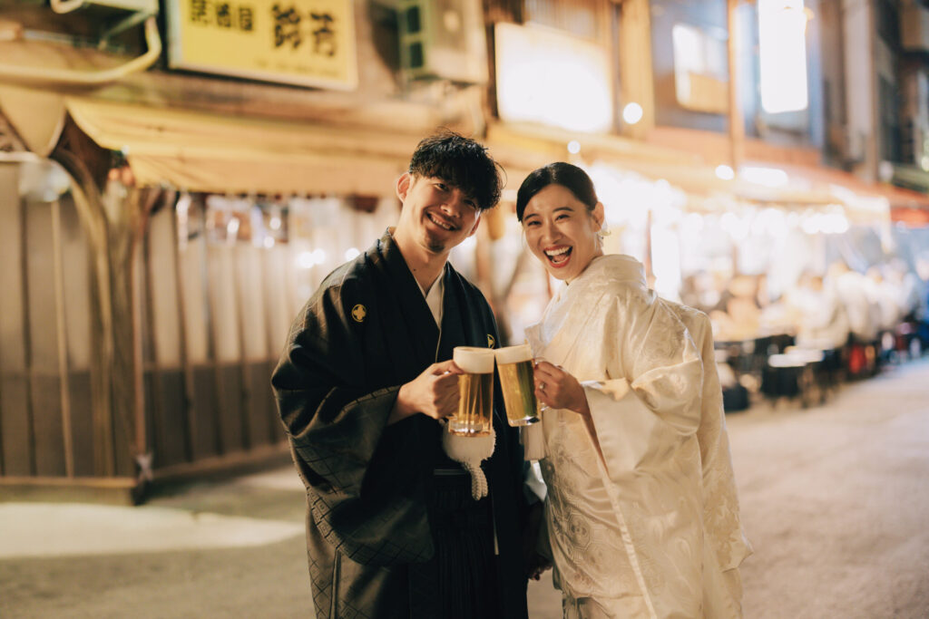 浅草の飲み屋街でビールジョッキを持って和装前撮りを楽しむカップル