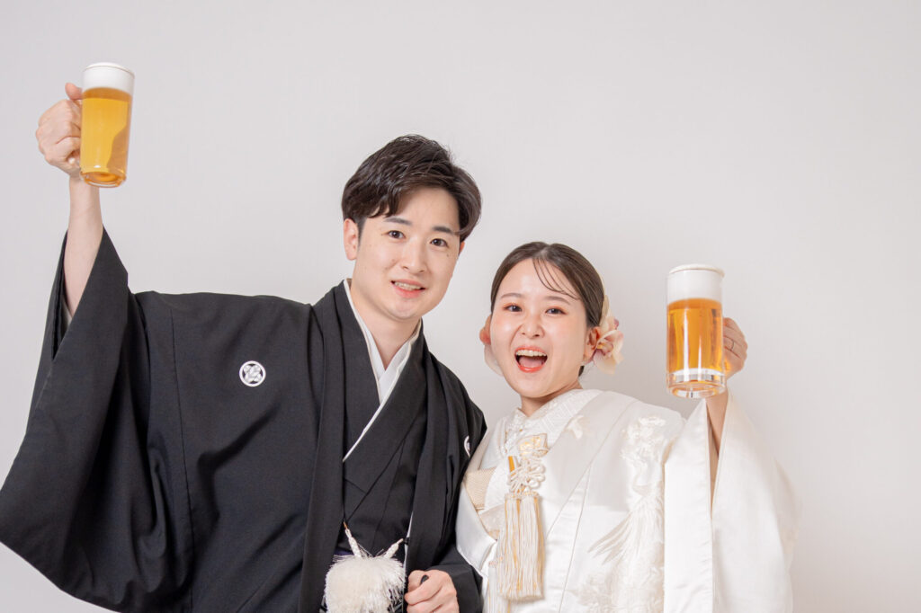 和装の新郎新婦がおもちゃのビールを片手に笑顔のショット