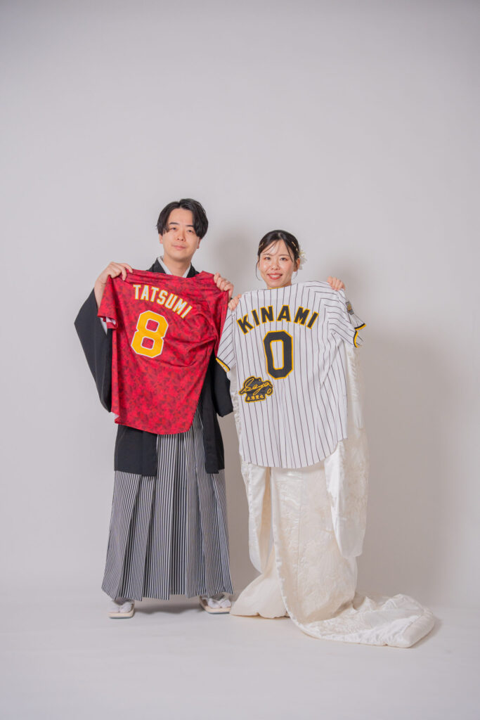 和装の新郎新婦が、想い出のユニフォームと一緒に撮影