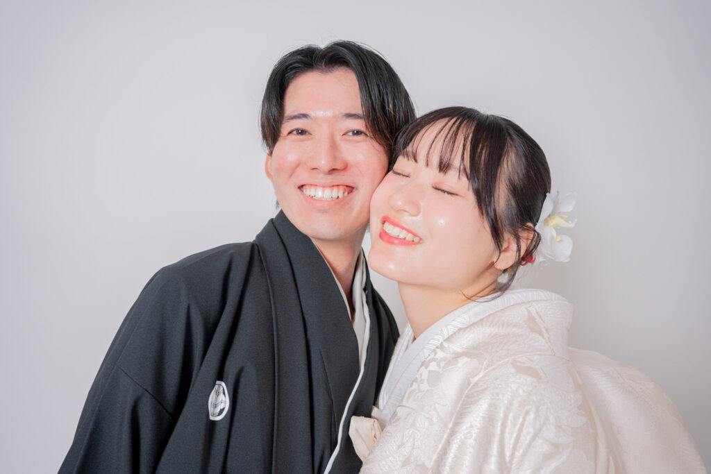 和装の新郎新婦が笑顔で頬密着ショット。幸せがあふれる。紋付き袴、白無垢