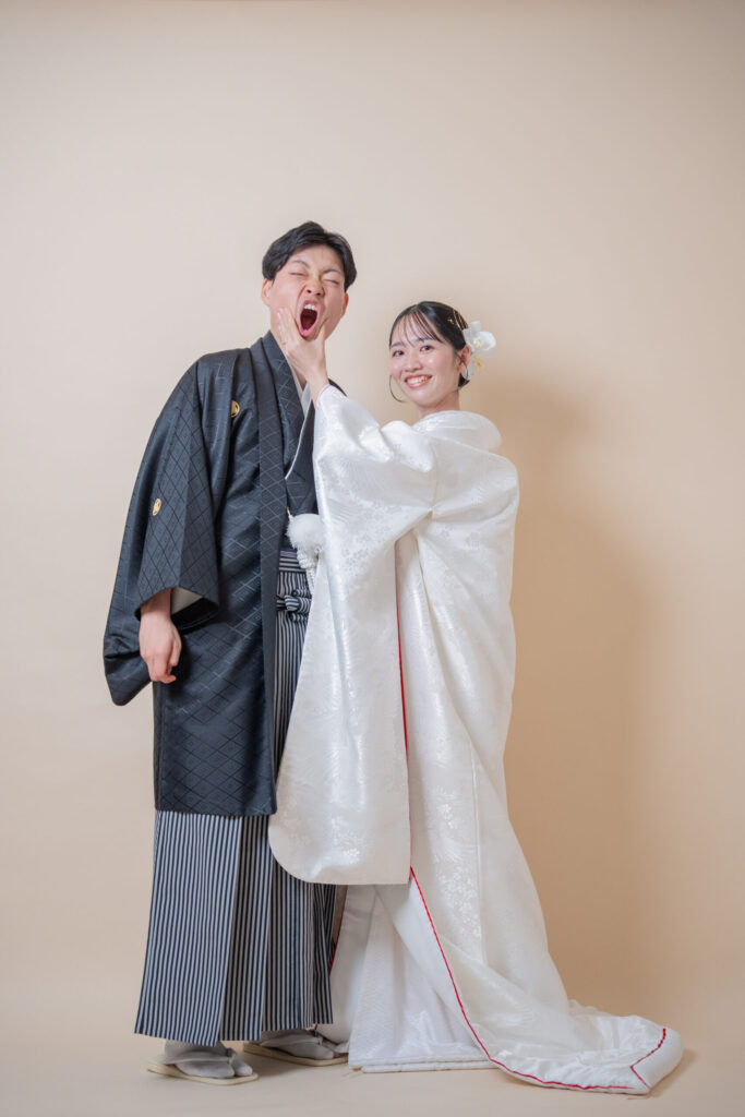 新譜が新郎の頬をぎゅっとつまむおふざけショット。紋付き袴と白無垢の和装におふざけポーズが印象的