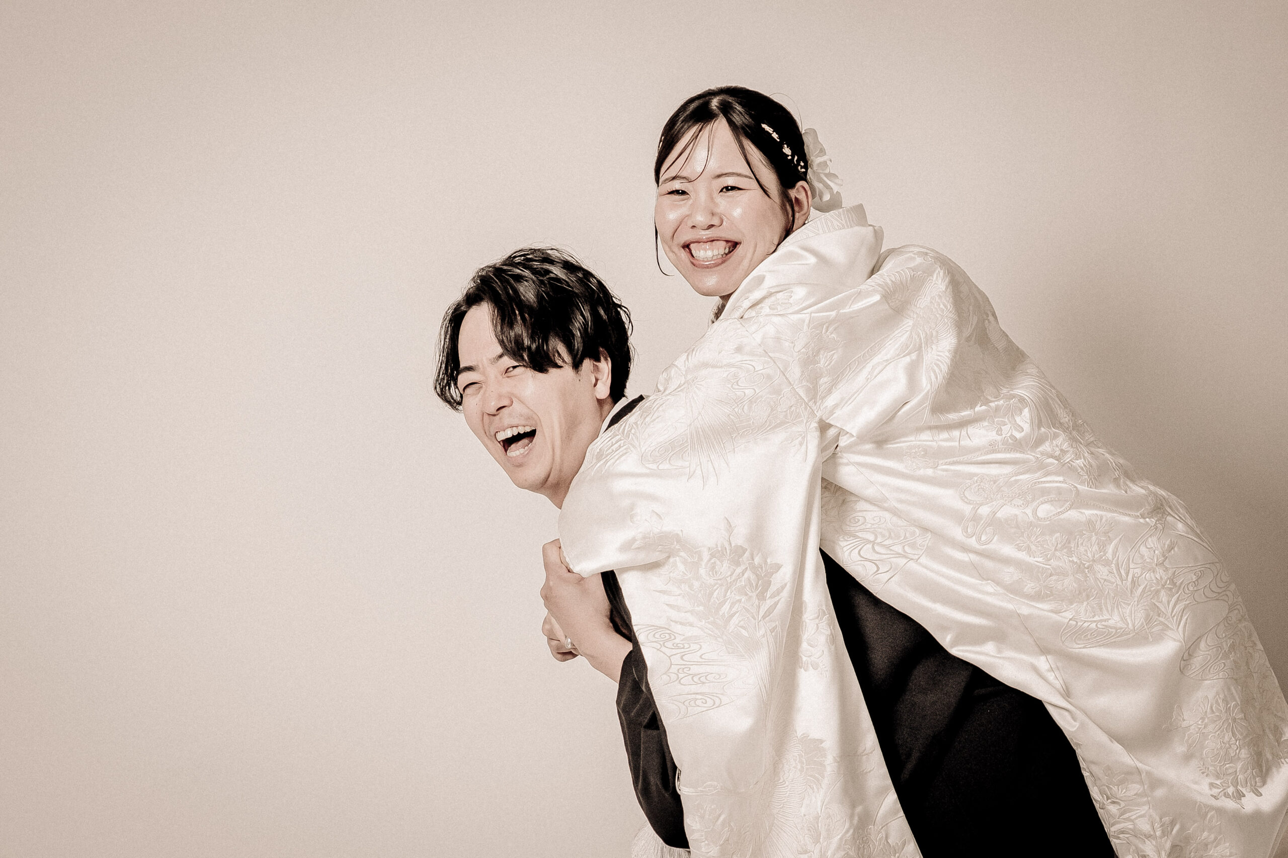 和装の新郎新婦。新郎のおんぶに、新婦が満面の笑み