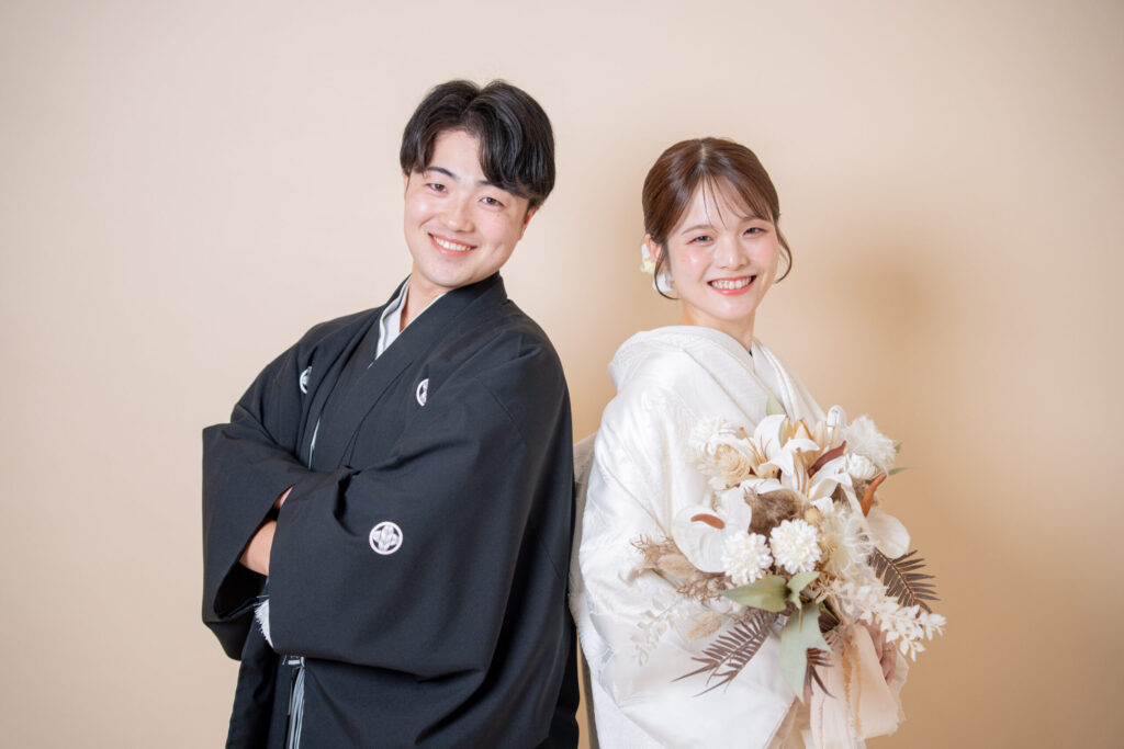 和装姿の新郎新婦が背中合わせで笑顔が印象的。自然な色合いのブーケがお二人の印象をより柔らかくしています