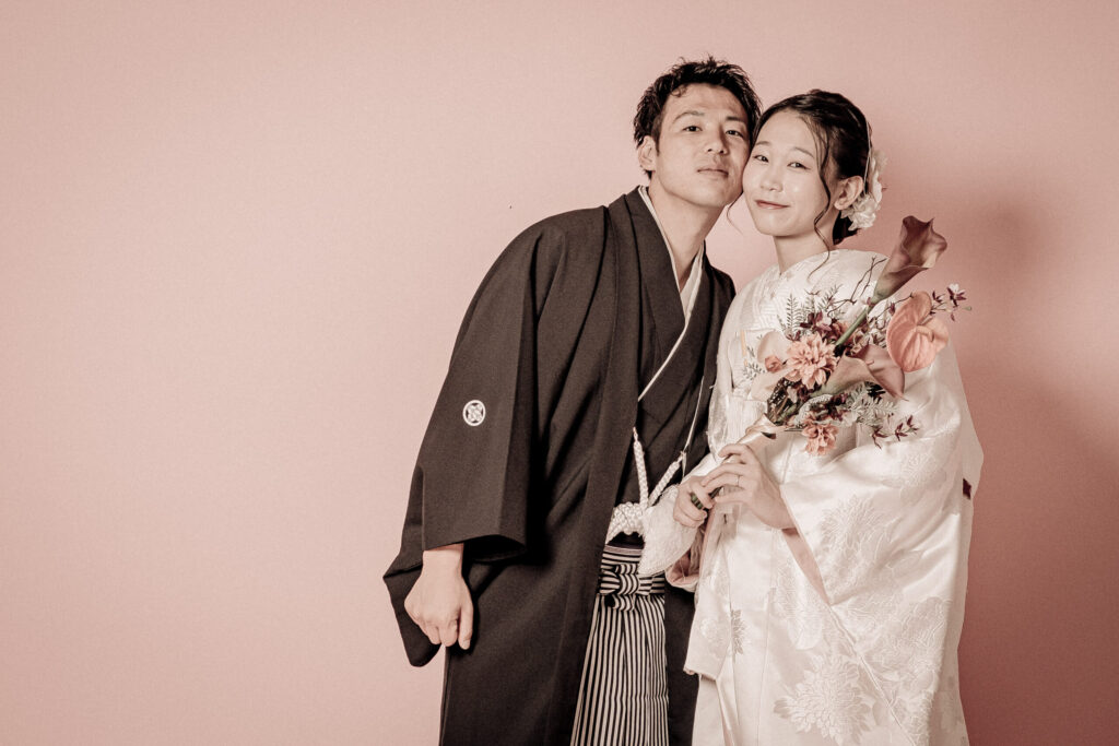 和装の新郎新婦が顔を寄せあう密着ショット。ブーケを片手にセピアに仕上げた紋付き袴、白無垢