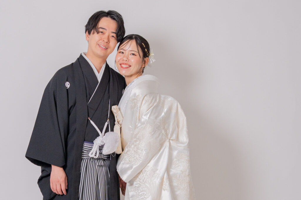 和装の新郎新婦が寄り添い笑顔の2ショット。紋付き袴、白無垢、和装ヘア