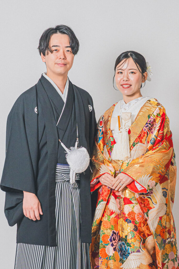 和装の新郎新婦が正面向かい合わせの王道ショット。紋付き袴、豪華な色打掛