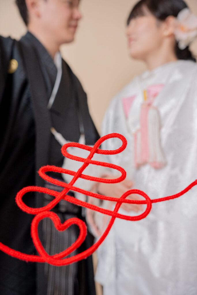 和装の新郎新婦が赤い色「寿」で愛を誓う2ショット。紋付き袴、白無垢