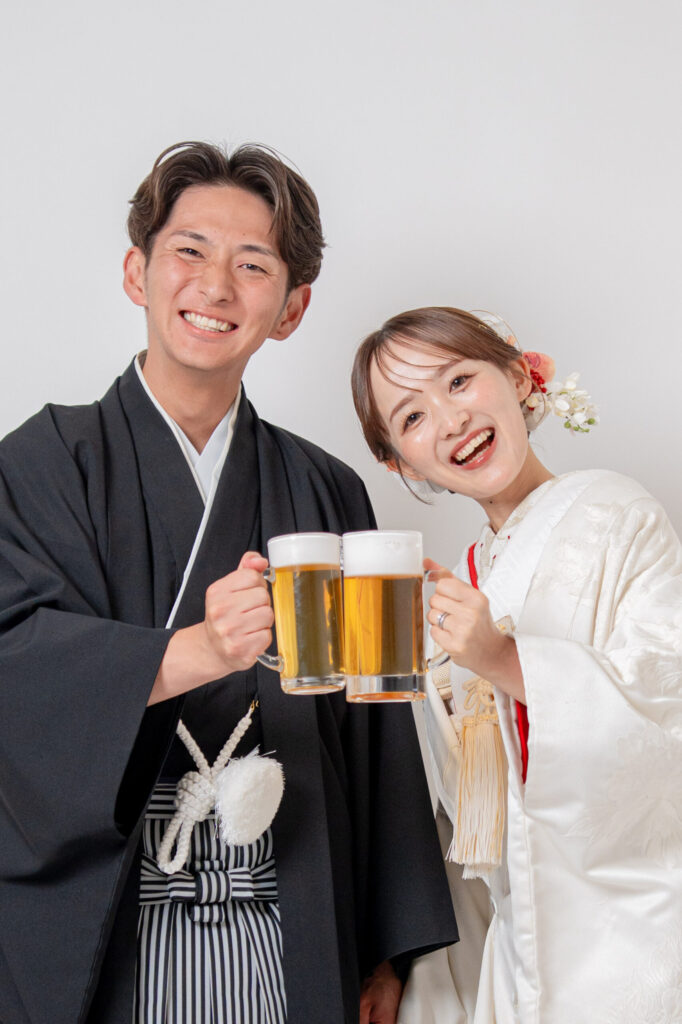 和装の新郎新婦がビールで乾杯。紋付き袴、白無垢