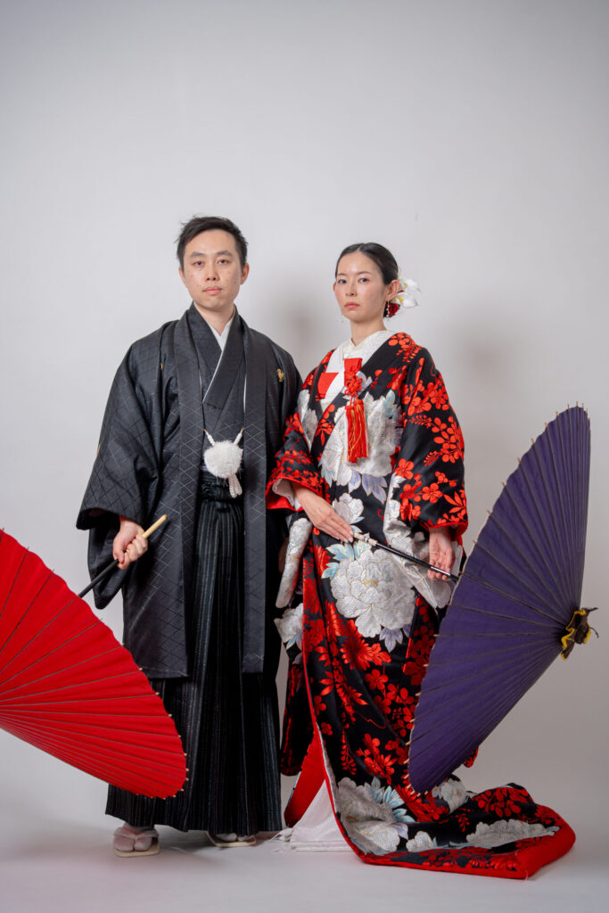 和装の2人が番傘を持った立ち姿で真顔ショット。紋付き袴、色打掛