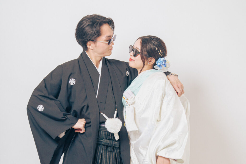 サングラスをかけた和装の新郎新婦が肩を組んで見つめあう海外風ショット。紋付き袴、白無垢