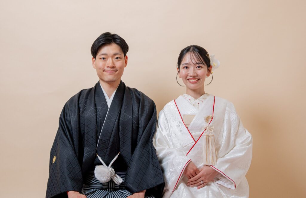 和装の新郎新婦が正面を向いた王道2ショット。紋付き袴、白無垢、座り姿勢。