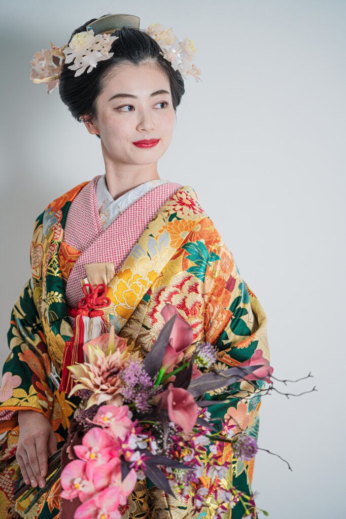 色打掛姿の花嫁がピンクの花のブーケを抱えてポーズをとる上半身ショット