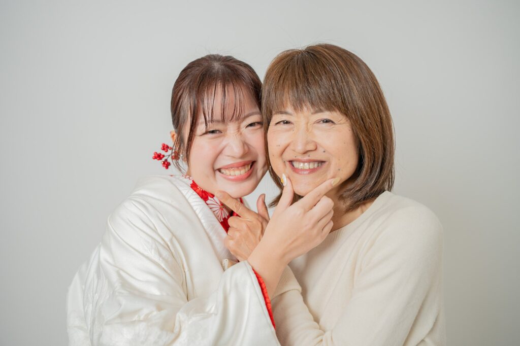 白無垢姿の花嫁が母親と頬を寄せ合って笑う家族ショット